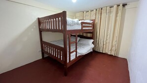 Ein Stockbett in einem Raum mit rotem Boden, weißen Wänden und einer Deckenleuchte.