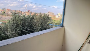 Ein kleiner Balkon mit Blick auf eine Stadtansicht, einem Mop und einem Eimer.