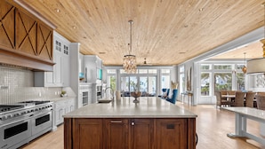 A spacious kitchen with a large island, wooden cabinetry, and a ceiling with exposed beams. - Splash — Largest Private Resort-Style Pool in Destin (Destin)