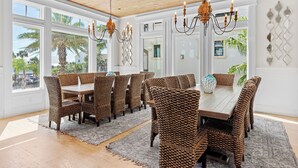A dining area with wicker chairs, a wooden table, and a chandelier. - Splash — Largest Private Resort-Style Pool in Destin (Destin)