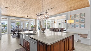 A spacious kitchen with a large island, wooden ceiling, and modern lighting fixtures. - Splash — Largest Private Resort-Style Pool in Destin (Destin)