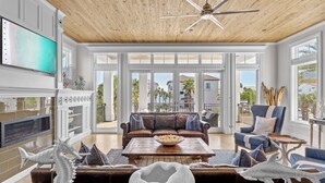 A spacious living room with a wooden ceiling, large windows, a leather sofa, and decorative seahorse sculptures. - Splash — Largest Private Resort-Style Pool in Destin (Destin)