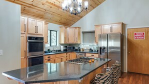 Une cuisine moderne avec des meubles en bois, des appareils électroménagers en acier inoxydable et un grand îlot central doté de tabourets de bar.