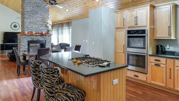 Une cuisine moderne dotée d’un îlot central, de meubles en bois et d’une cheminée en pierre.