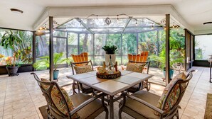 A conservatory with a glass ceiling, a dining table with chairs, and potted plants. - Safety Harbor Paradise (Safety Harbor)