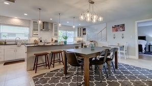 A modern kitchen with white cabinets, a central island, bar stools, and pendant lighting. - Safety Harbor Paradise (Safety Harbor)