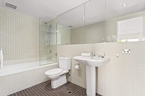A bathroom with a glass-enclosed shower, a white toilet, a white sink, and a mirror above the sink. - Beautiful Bondi 1-Bed Apartment Meters from Beach (Bondi Beach)
