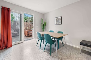 A room with a table, chairs, a bench, a door, and a framed picture on the wall.