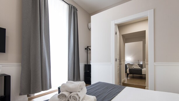 A hotel room with a bed, a TV, a desk, and a wardrobe. - Five Boutique Rooms - Camera 4 (Naples)
