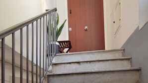 A staircase with a metal railing leading to a wooden door. - Five Boutique Rooms - Camera 4 (Naples)