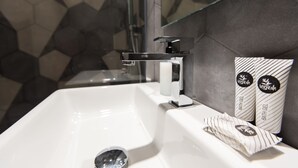 A modern bathroom with a white sink, a glass shower enclosure, and a hexagonal tile backsplash. - Five Boutique Rooms - Camera 5 (Naples)