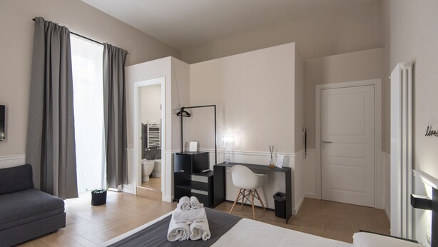 A modern hotel room with a bed, a desk, a chair, and a sofa. - Five Boutique Rooms - Camera 5 (Naples)
