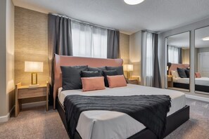 A modern hotel room with a large bed, two bedside tables, a mirror, and a carpeted floor. - Incredible villa with themed bedrooms by Disney (Kissimmee)