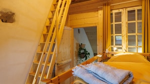 A wooden cabin interior with a bunk bed, a wooden staircase, and a window with curtains. - Graine de Bonheur gite ambiance chalet 7 persons (Chille)
