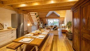 A wooden interior with a long dining table set for a meal, a staircase, and a view of the outdoors. - Graine de Bonheur gite ambiance chalet 7 persons (Chille)