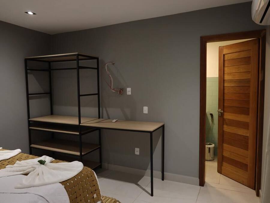 A bedroom with a bunk bed, a desk, and a chair. There is a door leading to another room.