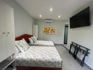 Een hotelkamer met twee bedden, een kledingkast, een flatscreen televisie en een schilderij aan de muur.