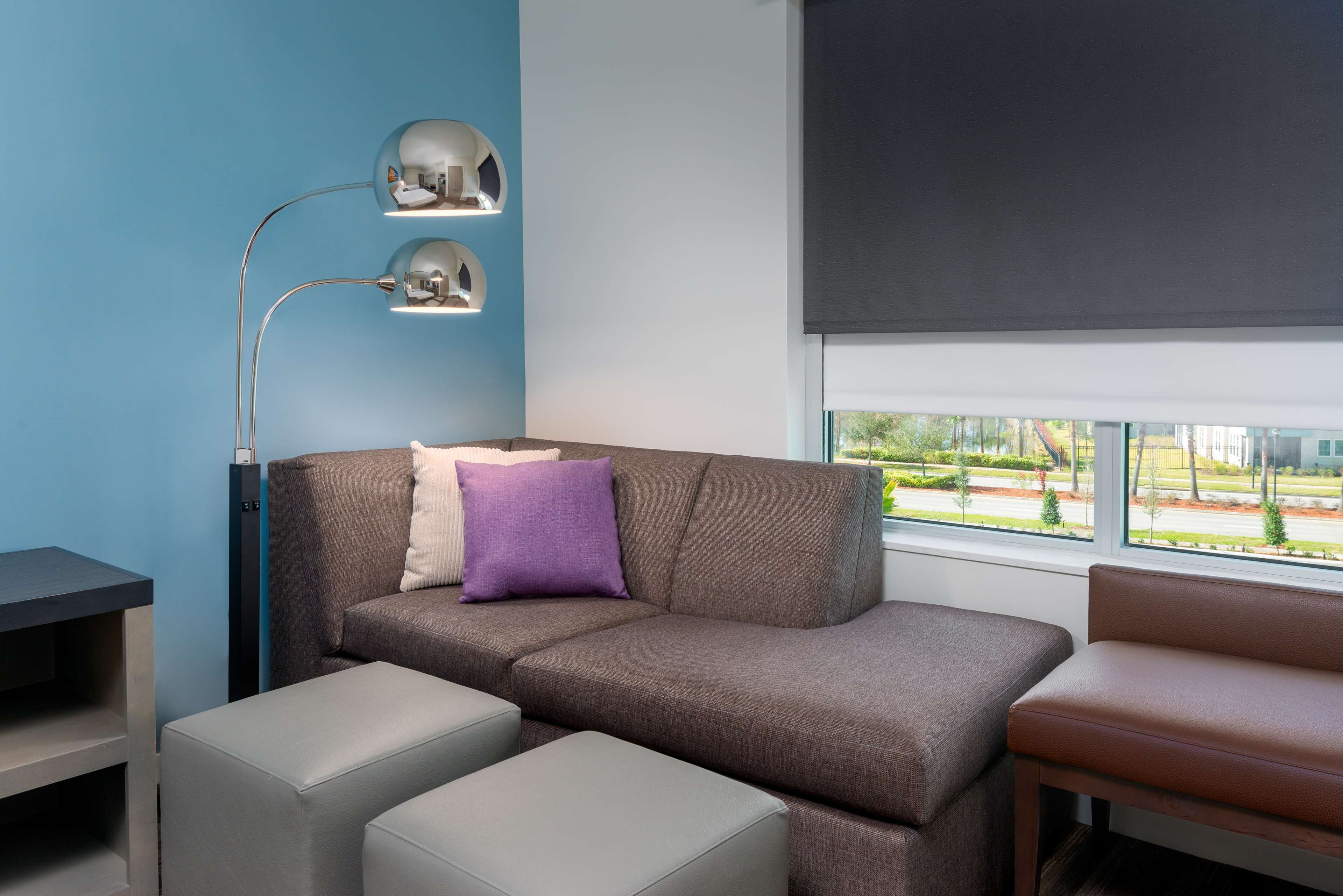 Un salon moderne avec un canapé d’angle, une petite table et un lampadaire.