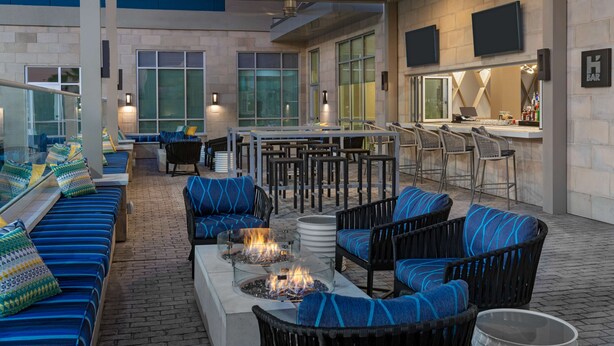 An outdoor patio area with seating, a bar, and a fire feature. - Hyatt House Orlando Airport (Orlando)