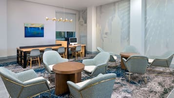 Una sala de conferencias moderna con una mesa redonda, varias sillas tapizadas, un escritorio de computadora y un cuadro abstracto grande en la pared.