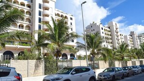 A multi-story hotel with balconies, palm trees, and parked cars. - Beautiful 2 levels apartment at the best beach area of Cancun hotel zone.... (Cancún)