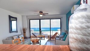 A modern living room with a wooden table, a sofa, and a large window overlooking the ocean. - Beautiful 2 levels apartment at the best beach area of Cancun hotel zone.... (Cancún)