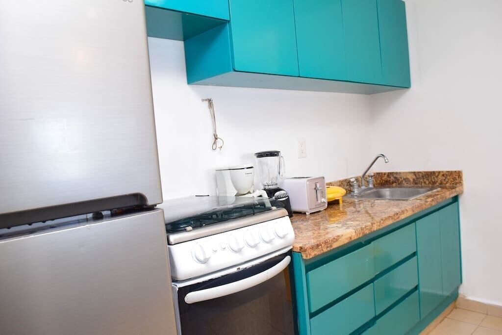 A kitchen with teal cabinets, a white stove, a toaster, and a sink.