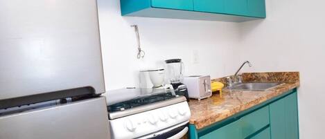 A kitchen with teal cabinets, a white stove, a toaster, and a sink.