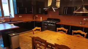 Una cocina con una mesa y sillas de madera, una estufa y armarios negros.