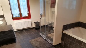 Un baño con bañera, cabina de ducha, inodoro y ventana con marco rojo.