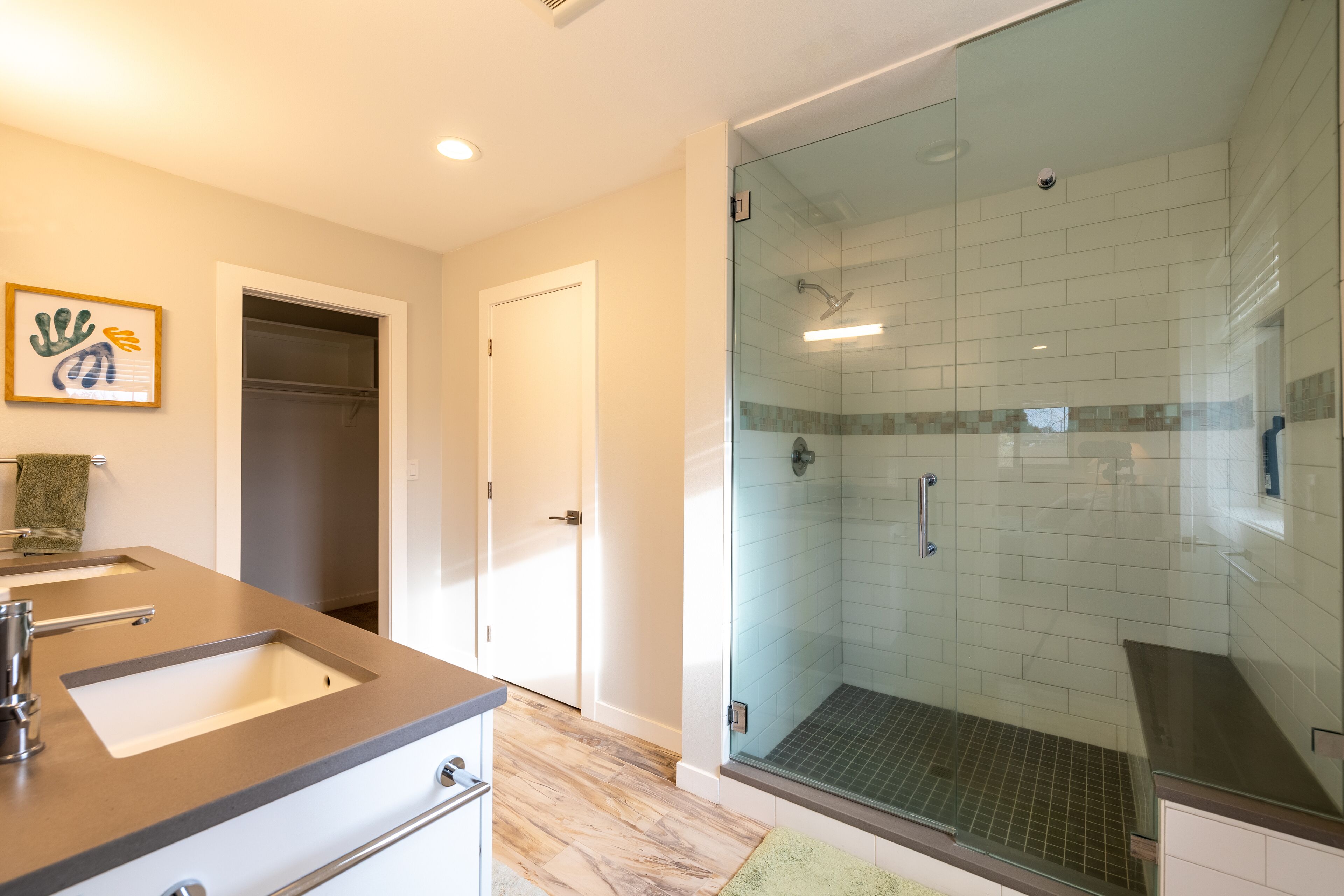 A modern bathroom with a glass-enclosed shower, a vanity with two sinks, and a towel rack.