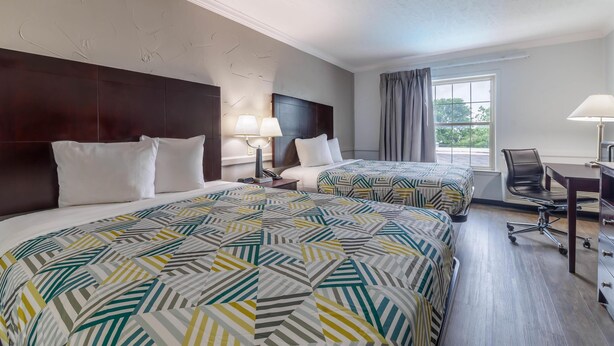 A hotel room with two beds, a desk, and a chair. - Studio 6 Suites - Dallas, TX - Downtown (Dallas)