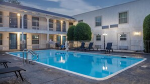 A swimming pool with lounge chairs and a building with balconies and windows. - Studio 6 Suites - Dallas, TX - Downtown (Dallas)
