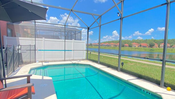 Une piscine extérieure couverte offrant une vue sur un lac et des maisons en arrière-plan.