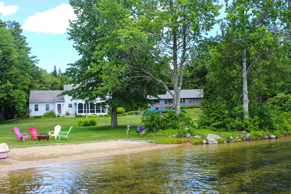 A lakeside property with a house, outdoor seating, and a dock.