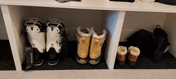 Een opbergruimte met diverse soorten schoeisel, waaronder skischoenen en laarzen met bontvoering.