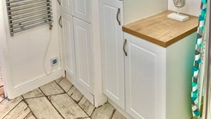 A corner room with white cabinets, a towel rack, a wooden shelf, and a seahorse decoration. - Stunning 3-bed Apartment in Ventnor (Ventnor)