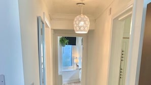 A hallway with a wooden floor, a rug, and a hanging light fixture. - Stunning 3-bed Apartment in Ventnor (Ventnor)