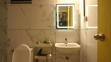 A modern bathroom with a marble floor, a white sink, a mirror with a light, and a toilet.