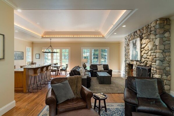 A spacious living area with a stone fireplace, leather sofas, and a dining area with high stools.