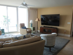 A living room with a sofa, armchair, and a television on a stand.