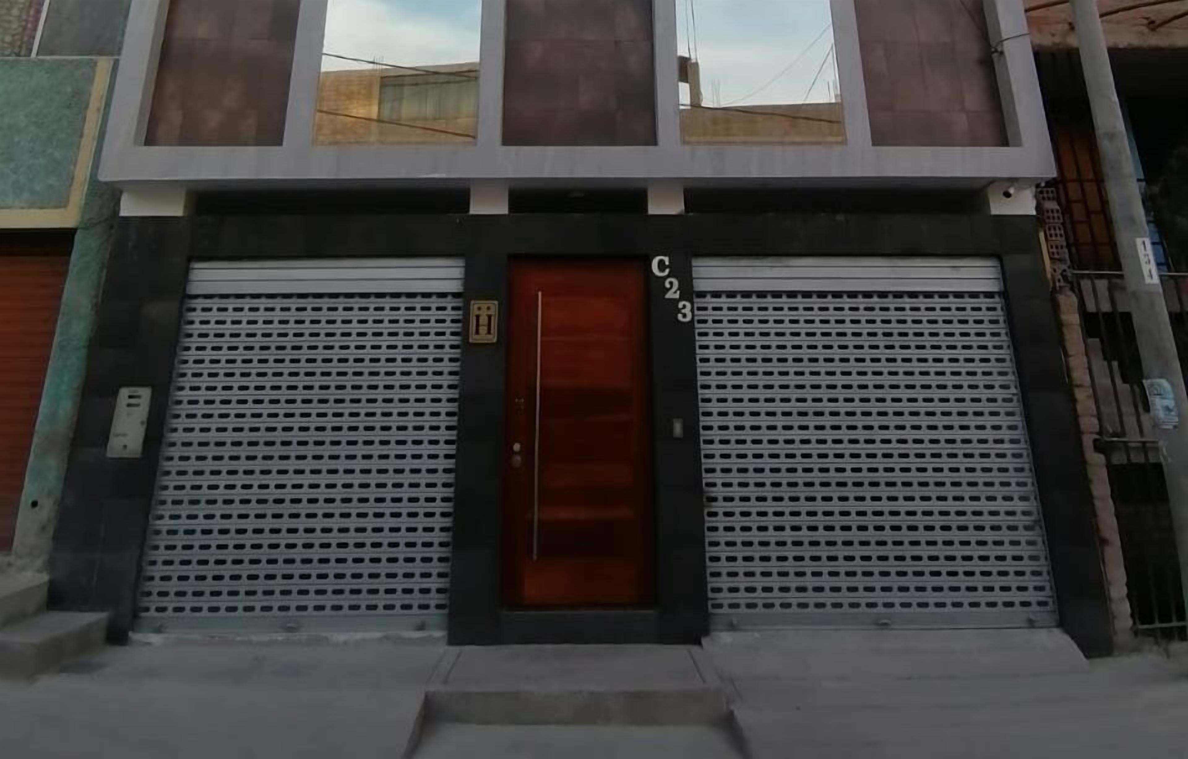 A building with a large garage door, a wooden door, and a sign with the number "C23".