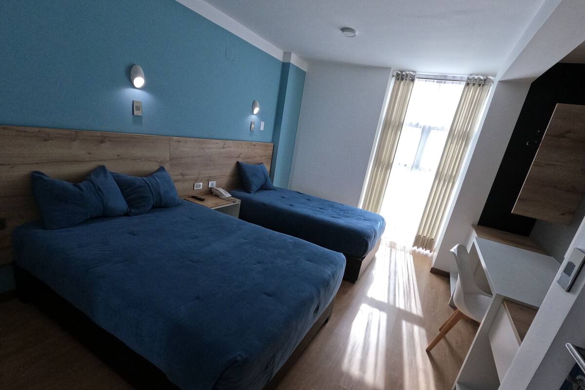 Habitación de hotel con dos camas, un escritorio y un televisor.