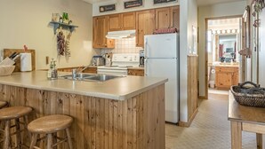 Eine Küche mit Holzausstattung, einer zentralen Kochinsel mit Barhocker, einem Kühlschrank und einer dekorativen Hängegarlic.
