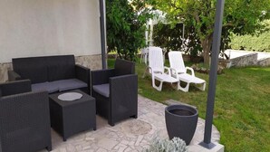 An outdoor seating area with dark wicker furniture, a round table, and a planter with a shrub. - Apartments Tea Medulin - One Bedroom Apartment with Terrace (Medulin)