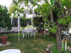 A white gazebo with a table and chairs in a garden setting.