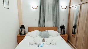 Ein ordentlich bezogenes Bett mit weißen Leinen, zwei Nachttische mit schwarzen Laternen und ein Holzschrank.