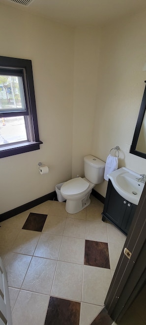 Et lille badeværelse med toilet, vask og vindue.