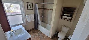 Ein Badezimmer mit Badewanne, Toilette, Waschbecken und Duschbereich.