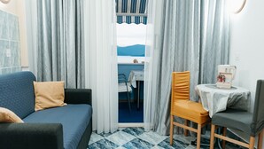 A room with a bed, a chair, a small table, and a view of the sea through a window. - Apartments Dragobratović - One Bedroom Apartment with Balcony and Sea View (Apartment 3) (Klek)